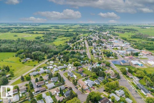 Aerial perspective showcasing a residential neighborhood surrounded by expansive green fields and distant tree lines - 4708 47A Avenue, Onoway, AB 