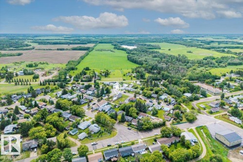 Aerial perspective showcasing a residential community surrounded by expansive green fields and forested areas - 4708 47A Avenue, Onoway, AB 