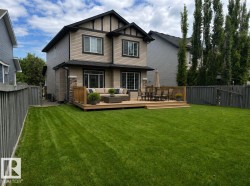 Spacious backyard featuring a large wooden deck with multiple levels, extensive lawn area, and privacy fencing - 