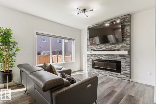 Living area featuring a stone veneer fireplace wall with a built-in electric fireplace and a floating white mantel - 19703 29 Avenue, Edmonton, AB 