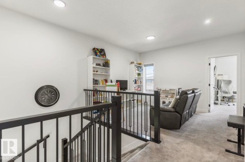 Upper-level landing featuring light gray carpeting, recessed lighting, and a black wrought iron railing - 19703 29 Avenue, Edmonton, AB 