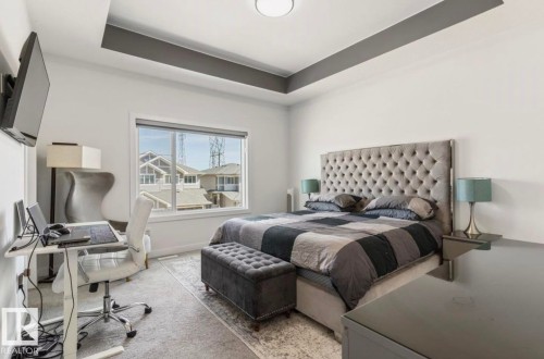 Spacious room featuring a tray ceiling with a contrasting accent, a large window, and carpet flooring - 19703 29 Avenue, Edmonton, AB 