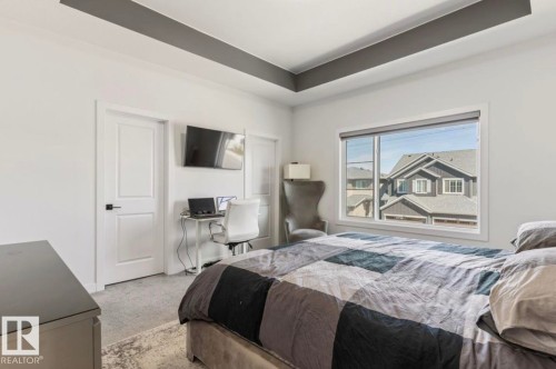 Spacious room featuring a tray ceiling with a dark accent, light gray carpet, and a large window - 19703 29 Avenue, Edmonton, AB 