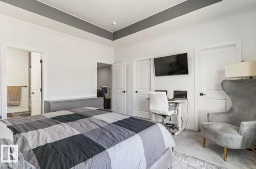 Spacious bedroom featuring a tray ceiling with a contrasting accent, carpeted flooring, and a built-in low-profile cabinet - 19703 29 Avenue, Edmonton, AB 