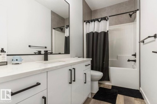 Contemporary bathroom featuring a white vanity with black hardware, a rectangular undermount sink, and a black single-handle faucet - 19703 29 Avenue, Edmonton, AB 