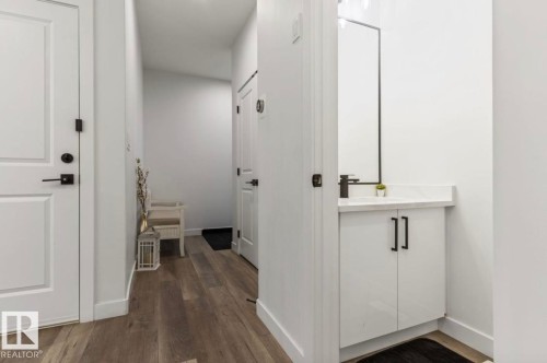 Modern bathroom vanity featuring white cabinetry with black hardware, a black framed mirror, and a black faucet - 19703 29 Avenue, Edmonton, AB 
