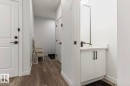 Modern bathroom vanity featuring white cabinetry with black hardware, a black framed mirror, and a black faucet - 19703 29 Avenue, Edmonton, AB 