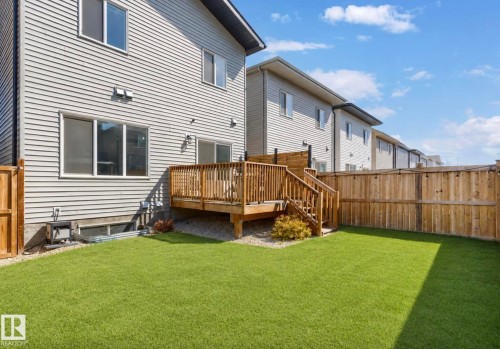 Fenced backyard featuring a wood deck with stairs, artificial turf, and gravel landscaping - 19703 29 Avenue, Edmonton, AB 