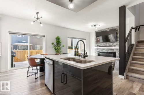 Open-concept living space with a kitchen island featuring a double-basin sink and a black gooseneck faucet - 19703 29 Avenue, Edmonton, AB 