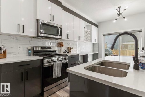 Modern kitchen featuring white upper cabinetry, dark lower cabinetry, and a white countertop - 19703 29 Avenue, Edmonton, AB 
