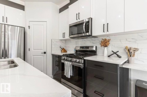 Modern kitchen featuring a stainless steel refrigerator, microwave, and gas range - 19703 29 Avenue, Edmonton, AB 