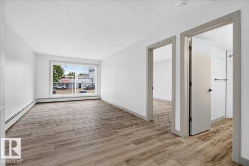 Spacious interior showcasing wood-finish flooring, white walls, and a large window - Edmonton, AB 