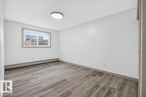 Spacious room featuring wood-finish flooring, white walls, and a contemporary flush-mount ceiling light - Edmonton, AB 