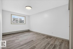 Spacious room featuring wood-finish flooring, white walls, and a contemporary flush-mount ceiling light - 