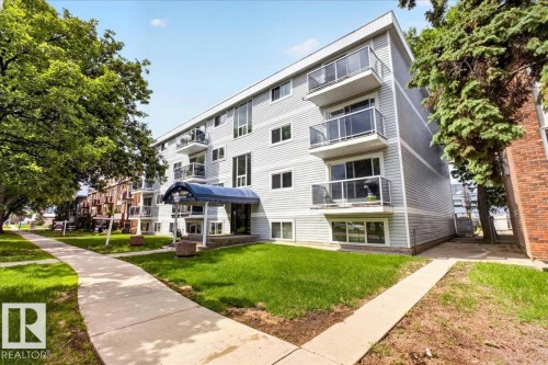 Multi-story building featuring gray horizontal siding and individual balconies with glass railings - Edmonton, AB 