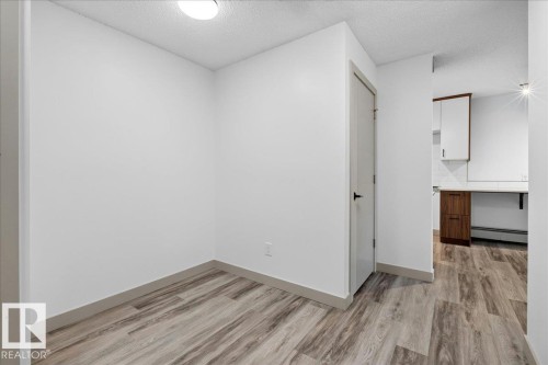Bright interior space featuring wood-finish flooring, white walls, and a flush-mount ceiling light - Edmonton, AB 