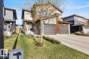Two-story residence featuring a combination of horizontal siding and stone accents, a double-car garage with two distinct doors, a concrete driveway, and a front lawn - 2847 Koshal Crescent, Edmonton, AB  - Outdoor 