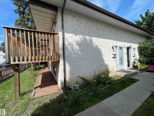 Exterior featuring a stucco finish, a raised wooden deck with railings, and dual glass-paneled entry doors - 8930B 144 Avenue, Edmonton, AB 