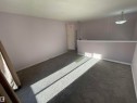 Carpeted interior space featuring light lavender walls, white baseboards, and a contemporary pendant light fixture - 8930B 144 Avenue, Edmonton, AB 