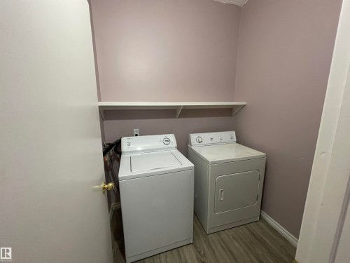 Dedicated laundry area featuring a shelf, wood-finish flooring, and light purple wall paint - 8930B 144 Avenue, Edmonton, AB 
