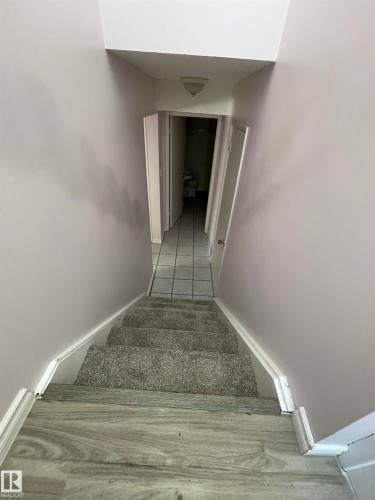 Stairwell featuring wood-finish flooring transitioning to gray carpeted stairs - 8930B 144 Avenue, Edmonton, AB 