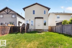 Rear exterior featuring beige siding, multiple windows, and a wooden deck with stairs providing yard access - 