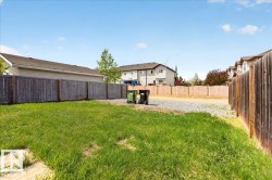 Expansive backyard featuring a large grass area and a perimeter wooden fence - 