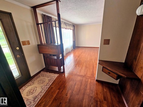 Entryway featuring wood-finish flooring, a built-in wood room divider with integrated cabinetry, and an opaque glass-paneled entry door - 7612 40 Avenue Nw, Edmonton, AB - Indoor Photo Showing Other Room