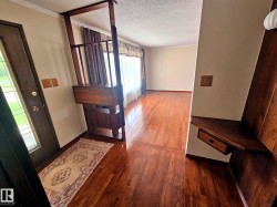 Entryway featuring wood-finish flooring, a built-in wood room divider with integrated cabinetry, and an opaque glass-paneled entry door - 