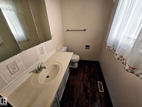 Vanity featuring an integrated sink, polished chrome faucet, and tiled backsplash - 7612 40 Avenue Nw, Edmonton, AB - Indoor Photo Showing Bathroom
