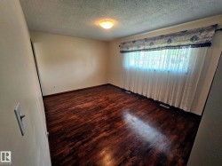 Spacious room featuring wood-finish flooring, neutral-toned walls, and a large window - 