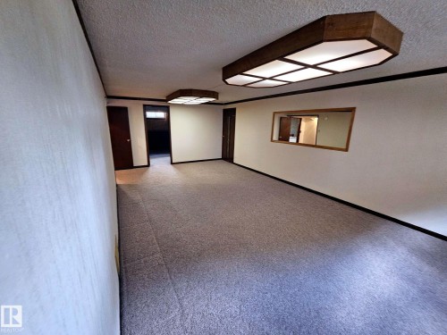 Carpeted room featuring multiple dark wood interior doors and trim - 7612 40 Avenue Nw, Edmonton, AB - Indoor Photo Showing Other Room