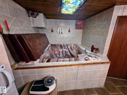 Indoor spa tub with a patterned interior, surrounded by light gray geometric wall tiling and a wood-finish ceiling - 