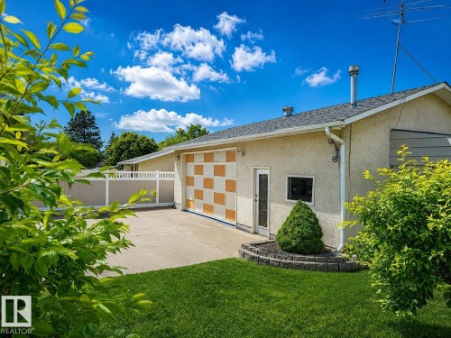Stucco exterior with a checkerboard pattern garage door and a concrete driveway - 7612 40 Avenue Nw, Edmonton, AB - Outdoor