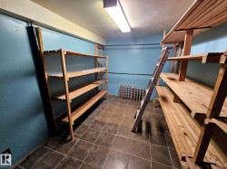 Utility room featuring extensive built-in wooden shelving, tile flooring, and a fluorescent ceiling light - 