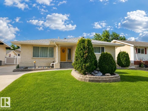 Ranch-style exterior featuring light-colored brick siding and a bright yellow front door - 7612 40 Avenue Nw, Edmonton, AB - Outdoor