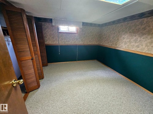Carpeted room featuring a drop ceiling with a light panel, a window with a valance, and a combination of painted lower walls with wood trim and patterned wallpaper - 7612 40 Avenue Nw, Edmonton, AB - Indoor Photo Showing Other Room
