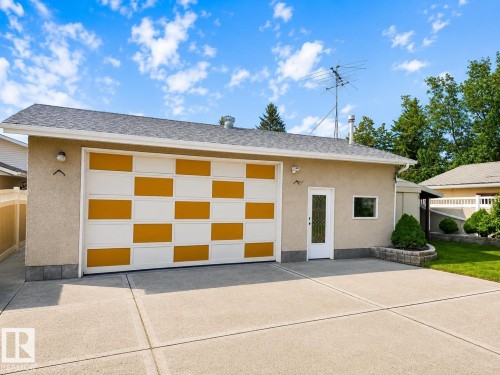 Detached garage featuring a contemporary checkered door design in gold and white, stucco exterior, and asphalt shingle roof - 7612 40 Avenue Nw, Edmonton, AB - Outdoor