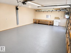 Spacious garage featuring a light gray finished floor, built-in wooden workbench, and a utility sink with cabinet - 