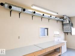 Workshop space featuring a built-in workbench, wall-mounted utility sink, and overhead fluorescent lighting - 