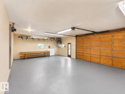 Spacious garage featuring a durable gray epoxy floor, a wide wooden garage door, and a built-in workbench with shelving - 