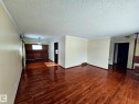 Spacious room with wood-finish flooring, light-toned walls, and white crown molding - 7612 40 Avenue Nw, Edmonton, AB  - Indoor Photo Showing Other Room 
