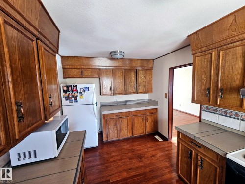 Kitchen featuring wood-finish cabinetry, tile countertops, and hardwood flooring - 7612 40 Avenue Nw, Edmonton, AB - Indoor Photo Showing Kitchen
