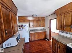 Kitchen featuring wood-finish cabinetry, tile countertops, and hardwood flooring - 