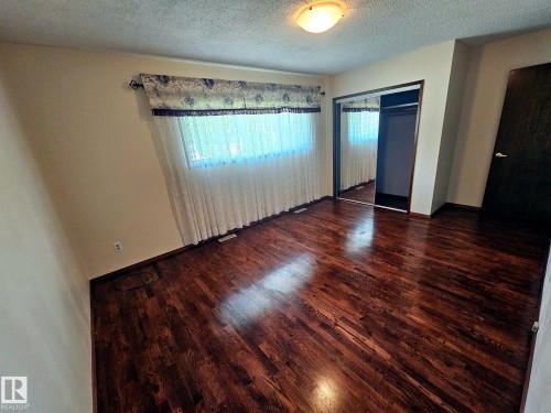 Rich wood-finish flooring complements the neutral wall tones - 7612 40 Avenue Nw, Edmonton, AB - Indoor Photo Showing Other Room