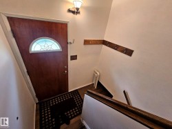 Front entry with a wood-finish door featuring a stained glass arched window - 