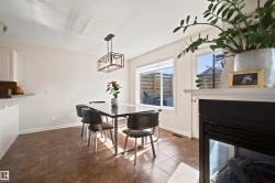 Dining area featuring a modern black framed chandelier, a built-in fireplace with a white mantel, and a large window - 