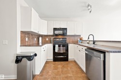 U-shaped kitchen featuring white cabinetry, dark countertops, brown tile backsplash, and coordinating tile flooring - 