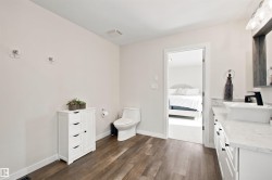 Bathroom featuring wood-finish flooring, a white vanity with a rectangular vessel sink, a black wall-mounted faucet, and a wall-mounted mirror - 