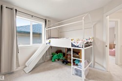 Bedroom featuring a large double-pane window, light gray carpeting, and a doorway leading to an additional space - 